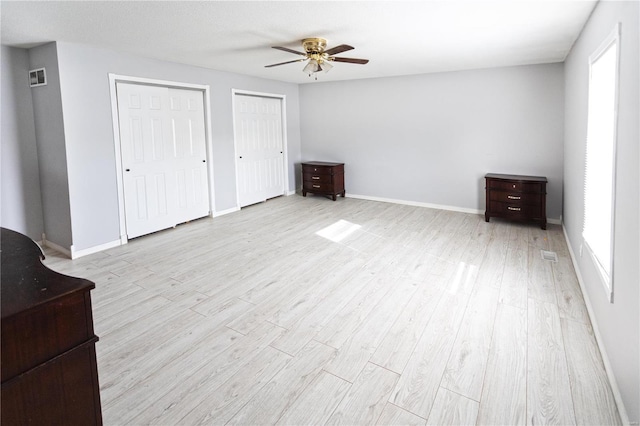 unfurnished bedroom with multiple closets, multiple windows, and light wood-type flooring