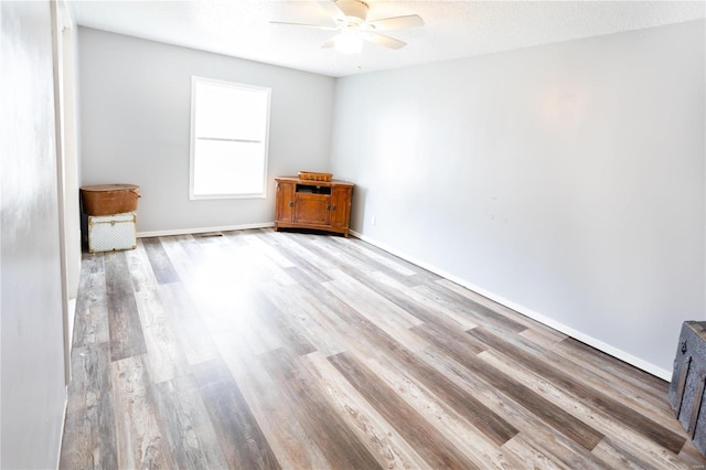 empty room with ceiling fan, a textured ceiling, and light wood-type flooring