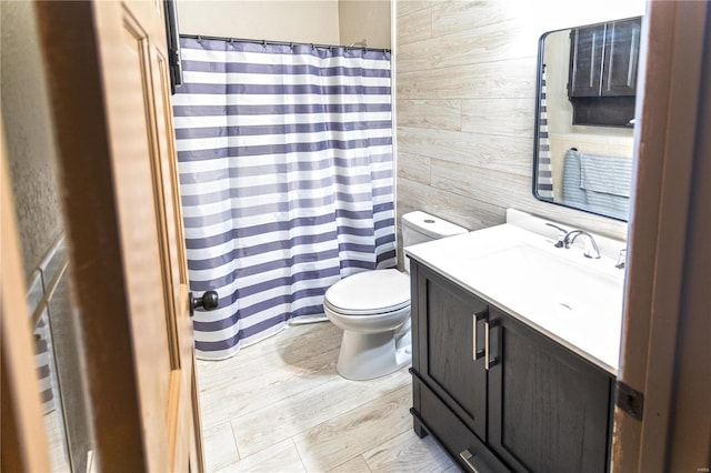 bathroom featuring toilet, vanity, wooden walls, and hardwood / wood-style floors