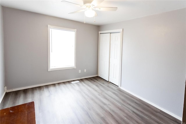 unfurnished bedroom featuring hardwood / wood-style floors, a closet, and ceiling fan