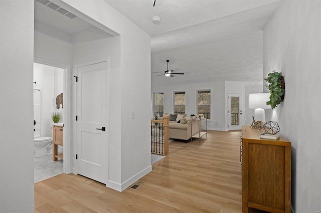 hallway with vaulted ceiling and light hardwood / wood-style floors