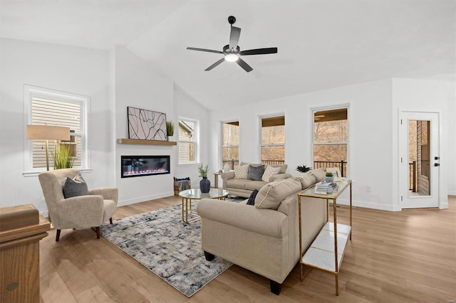 living room with ceiling fan, vaulted ceiling, and light hardwood / wood-style flooring