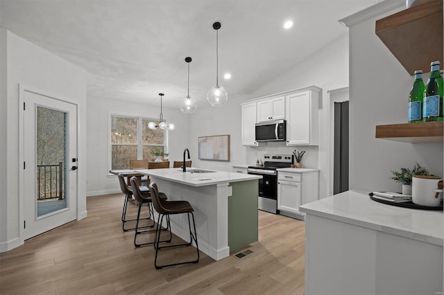 kitchen featuring appliances with stainless steel finishes, decorative light fixtures, white cabinetry, an island with sink, and sink