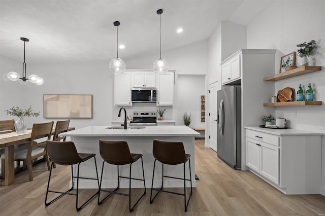 kitchen with sink, light hardwood / wood-style flooring, appliances with stainless steel finishes, pendant lighting, and white cabinets