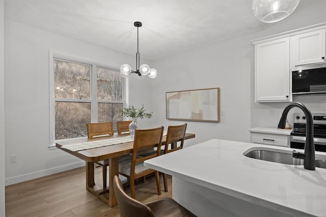 kitchen featuring a notable chandelier, sink, and light wood-type flooring