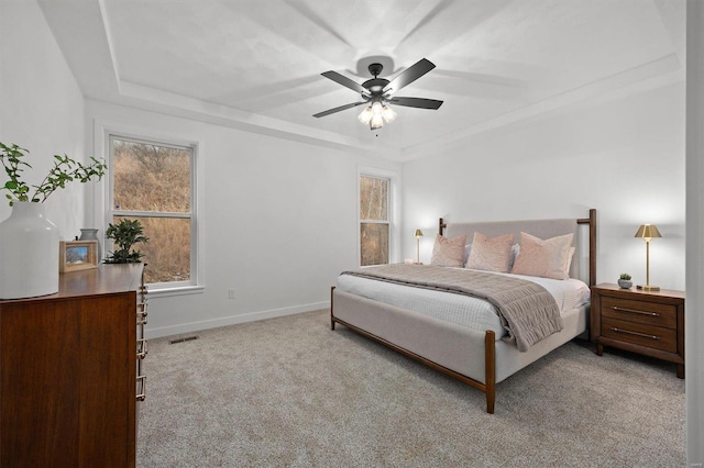 carpeted bedroom featuring ceiling fan and a tray ceiling