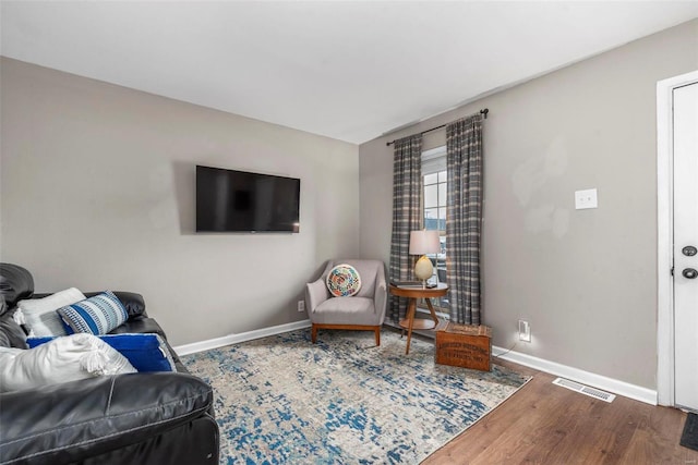 living room featuring baseboards, visible vents, and wood finished floors