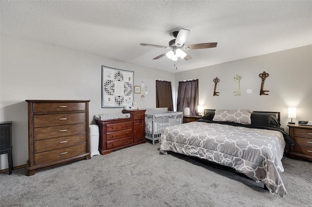 bedroom featuring a textured ceiling, ceiling fan, and light colored carpet