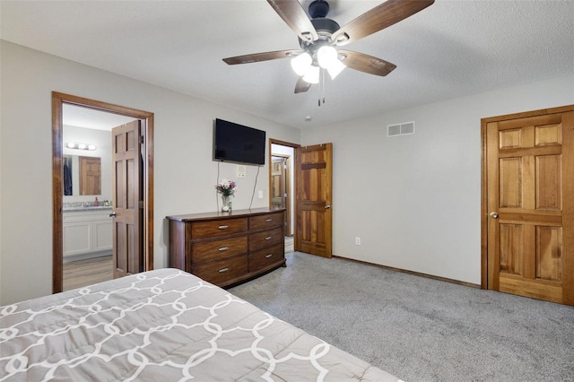 bedroom featuring light carpet, a ceiling fan, visible vents, baseboards, and ensuite bath