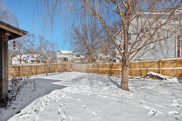 yard layered in snow with a fenced backyard