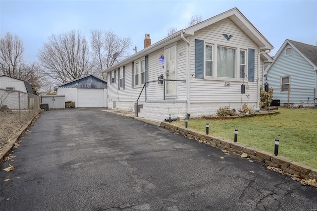 view of front facade with a garage, an outdoor structure, and a front lawn