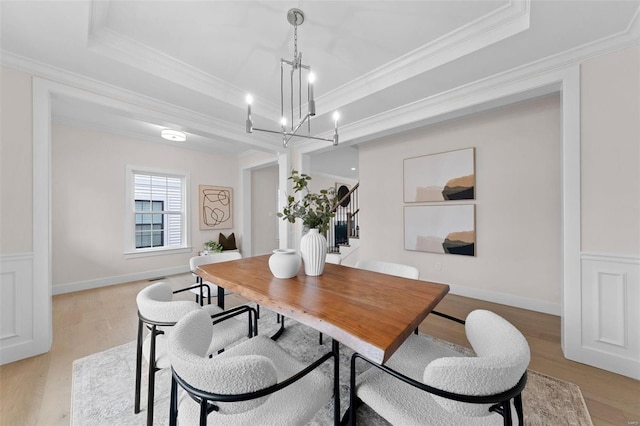 dining room with ornamental molding, a raised ceiling, and light wood-style flooring