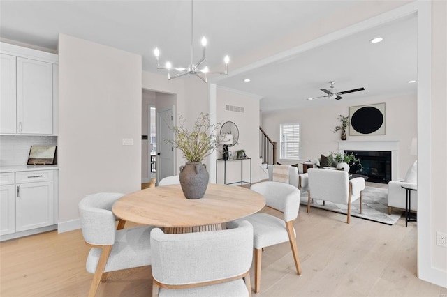 dining room featuring a glass covered fireplace, stairway, light wood finished floors, and recessed lighting