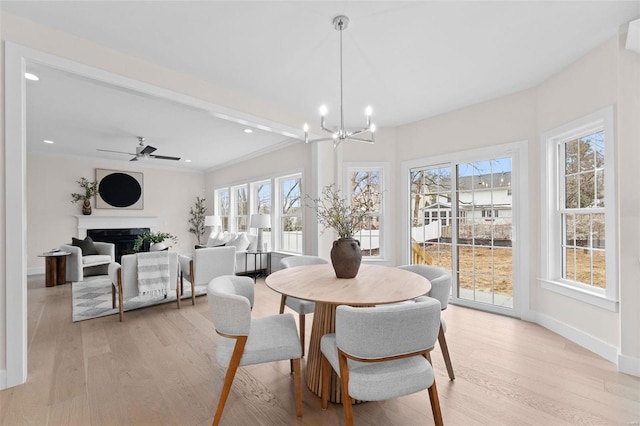 dining room with crown molding, light wood finished floors, a fireplace, and baseboards