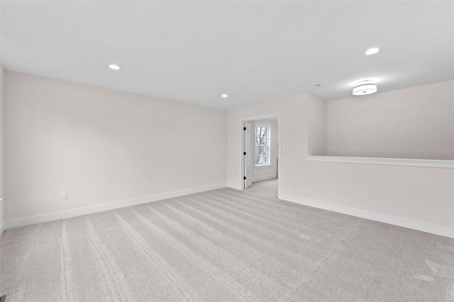 spare room featuring recessed lighting, light colored carpet, and baseboards