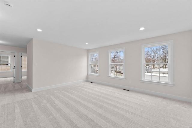 spare room featuring recessed lighting, light carpet, and baseboards