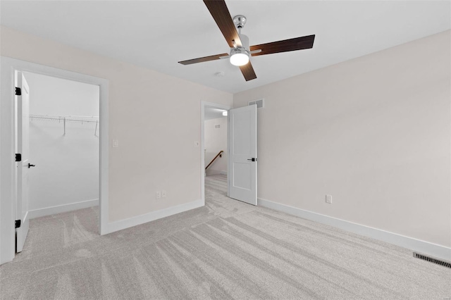 unfurnished bedroom featuring a spacious closet, carpet flooring, visible vents, and baseboards