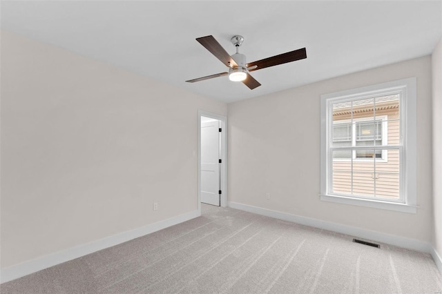 spare room featuring a ceiling fan, visible vents, light carpet, and baseboards