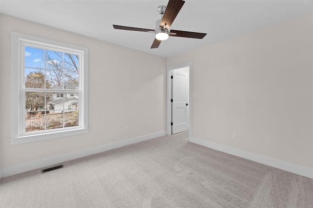 carpeted spare room with a ceiling fan, visible vents, and baseboards