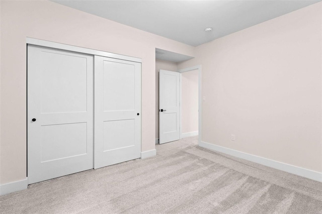 unfurnished bedroom featuring carpet, baseboards, and a closet