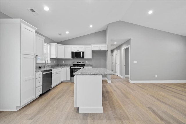 kitchen with visible vents, appliances with stainless steel finishes, a center island, light stone countertops, and white cabinetry