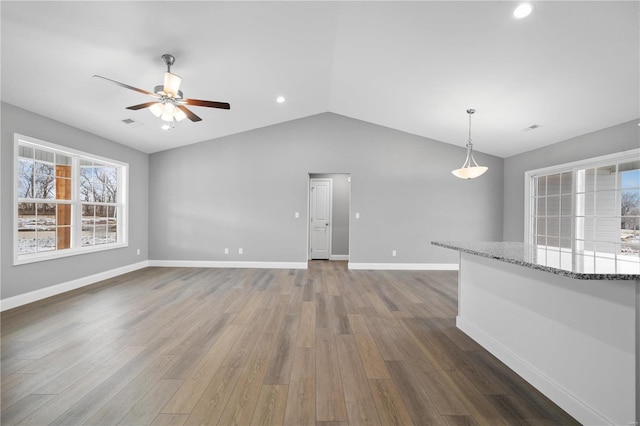 unfurnished living room with lofted ceiling, ceiling fan, dark wood finished floors, and baseboards