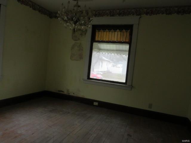 empty room featuring hardwood / wood-style floors and an inviting chandelier