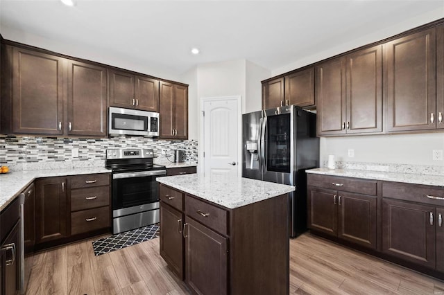 kitchen featuring tasteful backsplash, a center island, dark brown cabinetry, light wood-type flooring, and stainless steel appliances