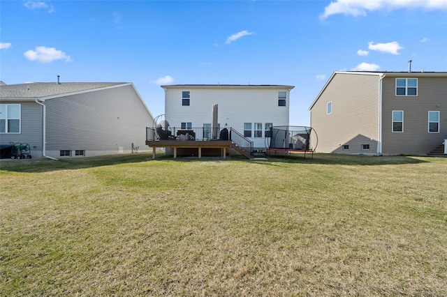 back of house featuring a yard, a trampoline, and a deck