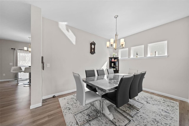 dining space with a notable chandelier, baseboards, and wood finished floors