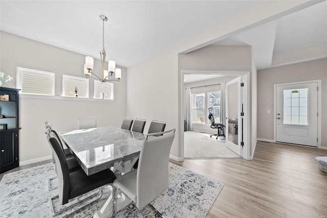 dining area with light wood finished floors, baseboards, and an inviting chandelier