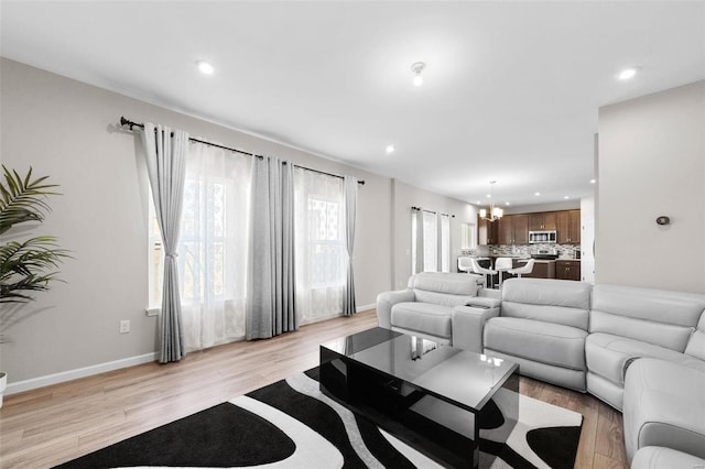 living area with recessed lighting, light wood-type flooring, baseboards, and a chandelier