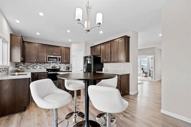 kitchen with a sink, backsplash, a center island, stainless steel appliances, and dark brown cabinetry