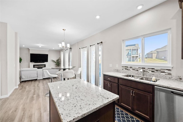 kitchen with light wood finished floors, a sink, dark brown cabinetry, dishwasher, and backsplash