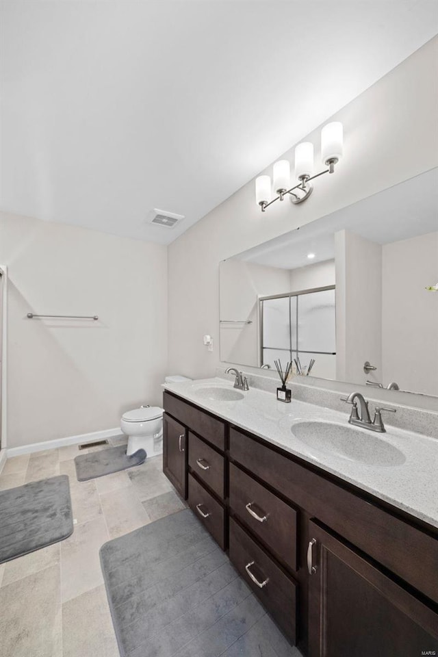 bathroom with double vanity, visible vents, a stall shower, and a sink