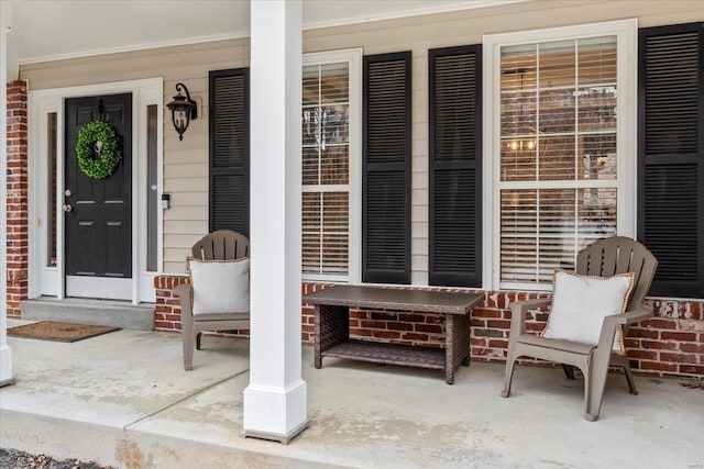 doorway to property featuring brick siding and covered porch