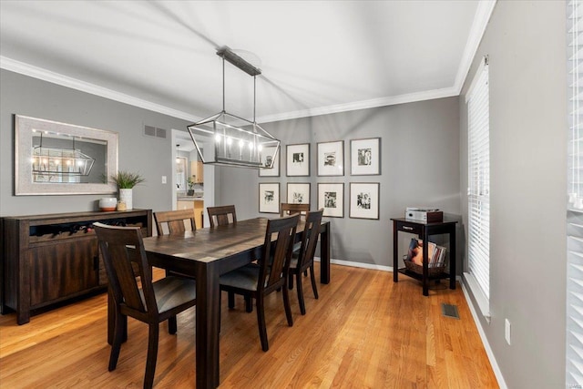 dining room featuring visible vents, light wood-style floors, an inviting chandelier, and crown molding