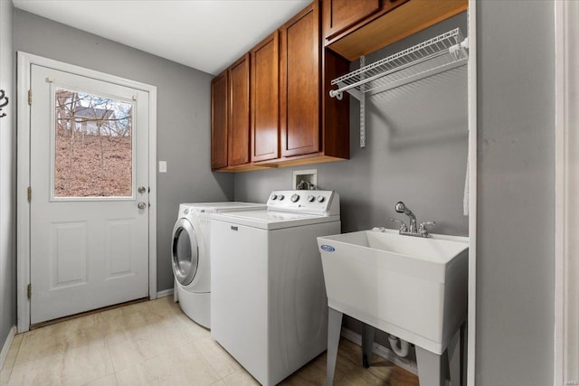 clothes washing area featuring cabinet space, separate washer and dryer, and a sink