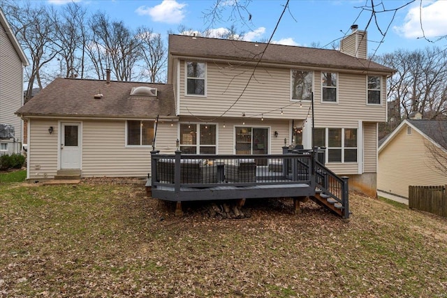 back of house with a deck, a yard, and a chimney