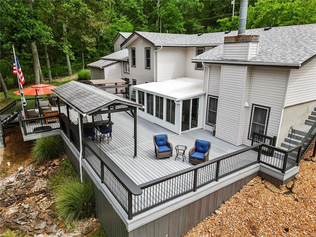 back of house with roof with shingles, a chimney, a gazebo, a sunroom, and a wooden deck