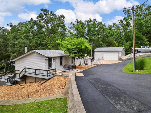 single story home with a shingled roof, a detached garage, a deck, and an outdoor structure