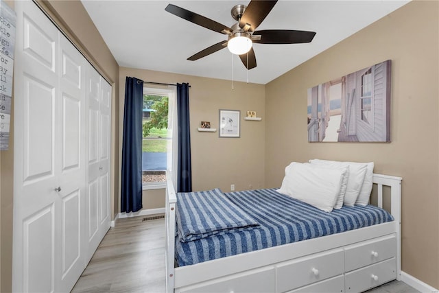 bedroom featuring a ceiling fan, visible vents, baseboards, a closet, and light wood finished floors