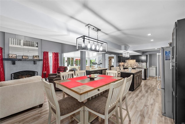dining room featuring light wood finished floors, a fireplace, and recessed lighting