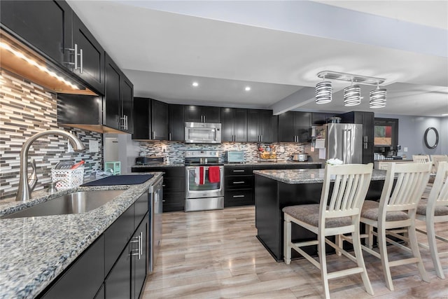 kitchen with appliances with stainless steel finishes, backsplash, a sink, and dark cabinetry