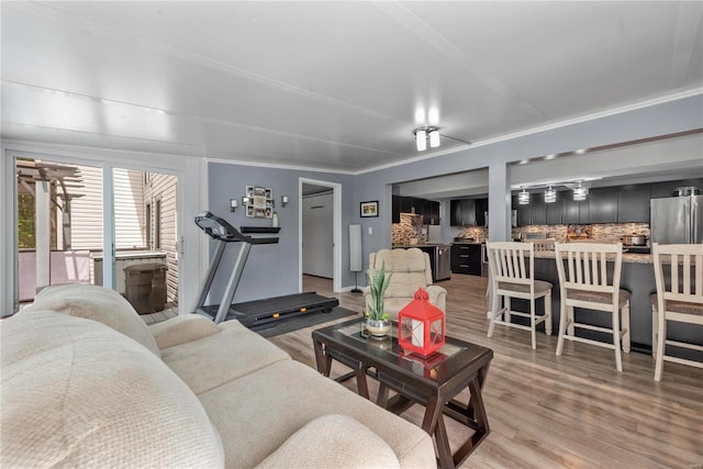 living area with light wood-type flooring and ornamental molding