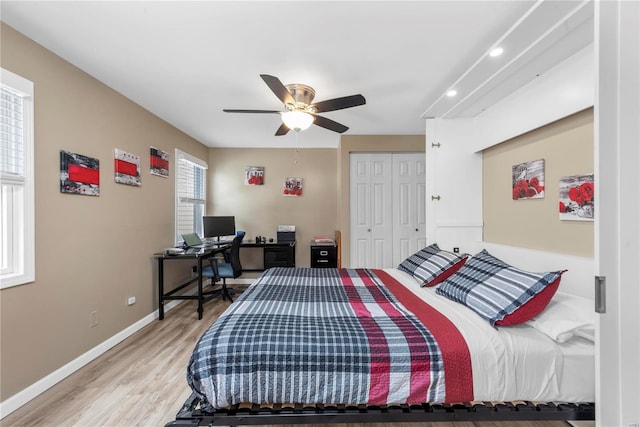 bedroom featuring ceiling fan, a closet, light wood-style flooring, and baseboards