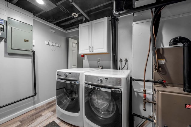 clothes washing area featuring light wood-type flooring, cabinet space, baseboards, and washer and clothes dryer