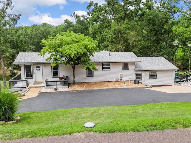 view of front of property featuring driveway, a shingled roof, a front lawn, and a porch