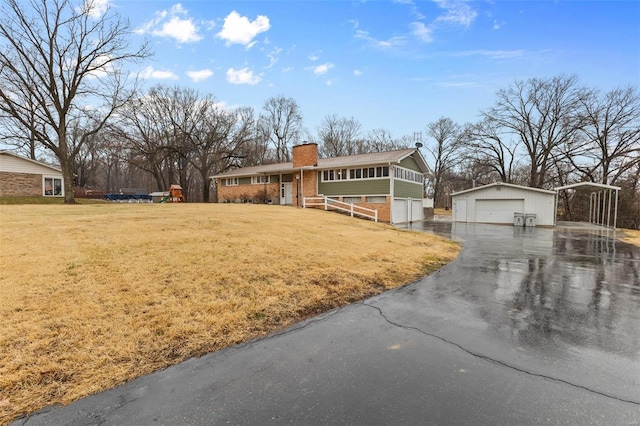 view of front facade with a garage, an outbuilding, and a front lawn