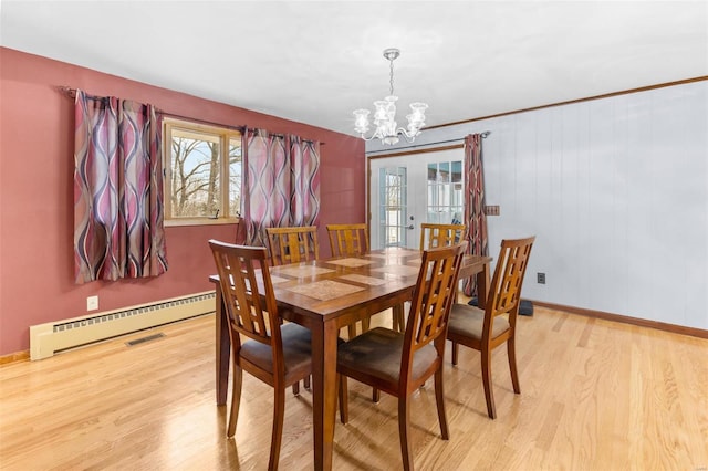 dining area featuring light wood-type flooring, a notable chandelier, baseboard heating, and french doors